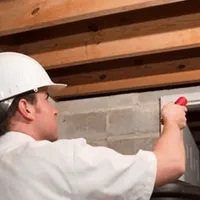 Termite inspection technician checking a basement wall and framing for termite activity in Worcester, MA